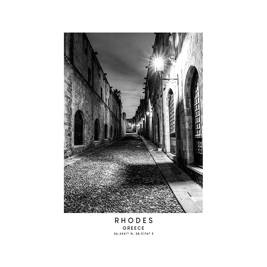 Black and white street scene in Rhodes, Greece with cobblestone pavement and old buildings.