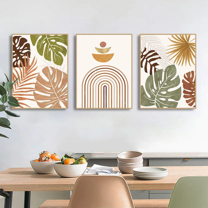 Three framed artworks with leaf and abstract designs above a dining table with food.