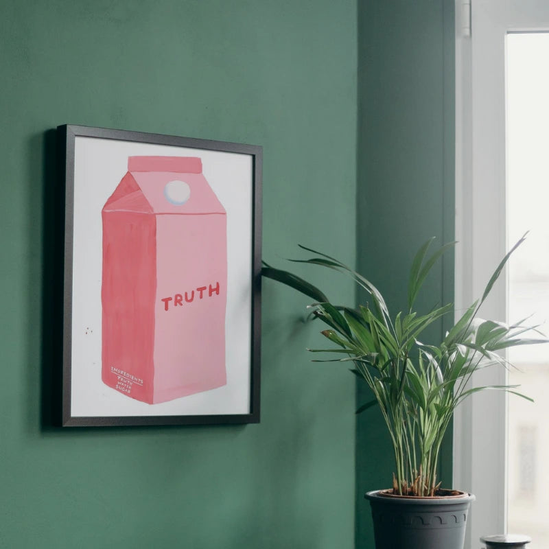 Framed artwork of a pink milk carton with 'TRUTH' on a green wall, next to a potted plant.