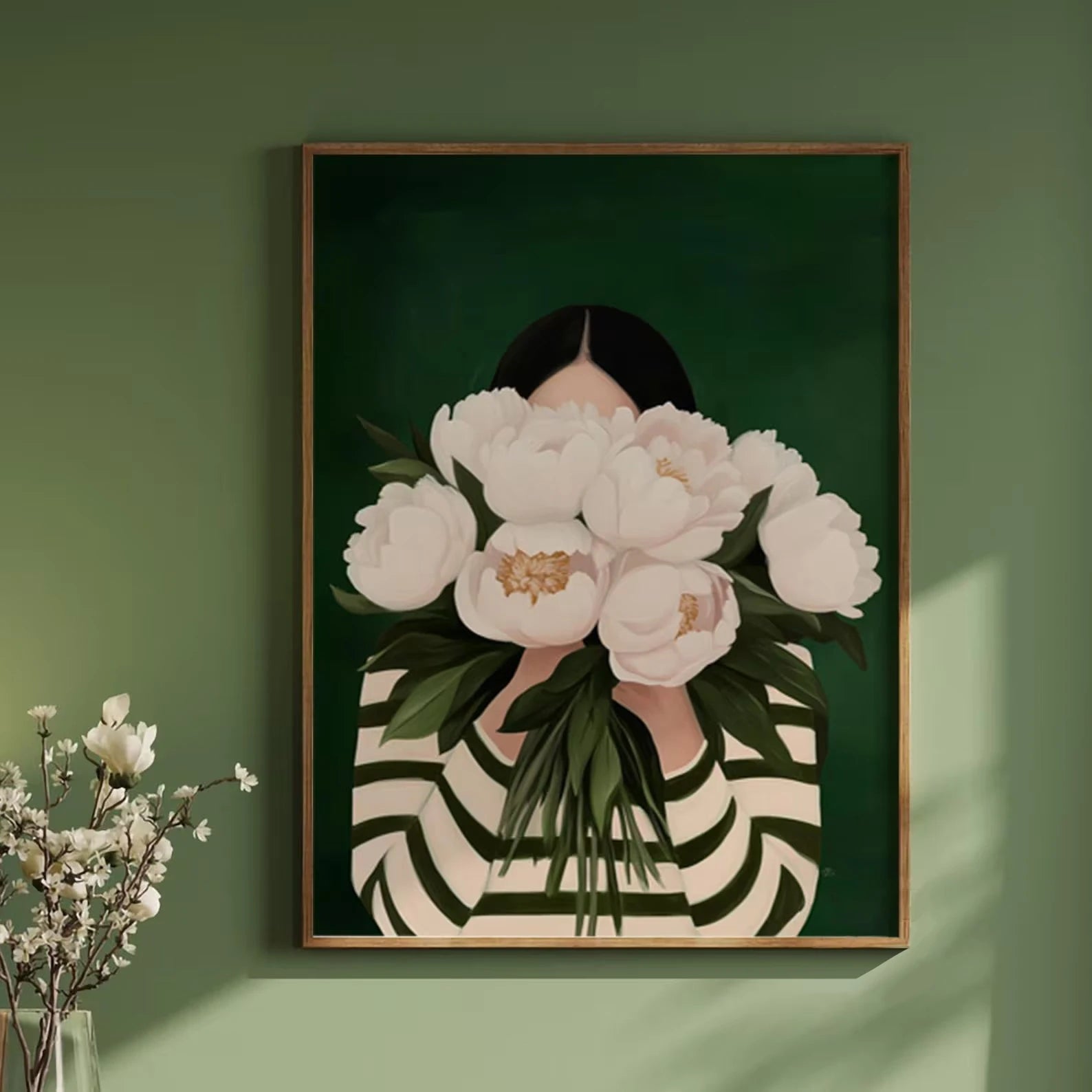 Framed artwork of a person holding white flowers against a green wall.