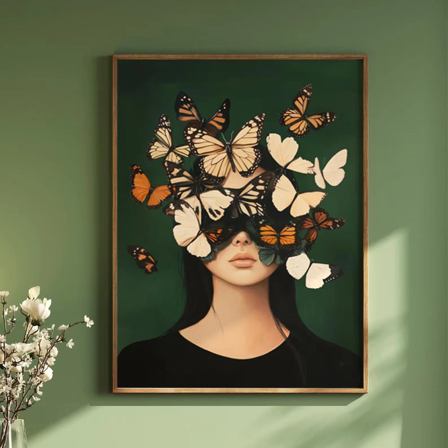 Framed artwork of a woman's face with butterflies on a green wall.