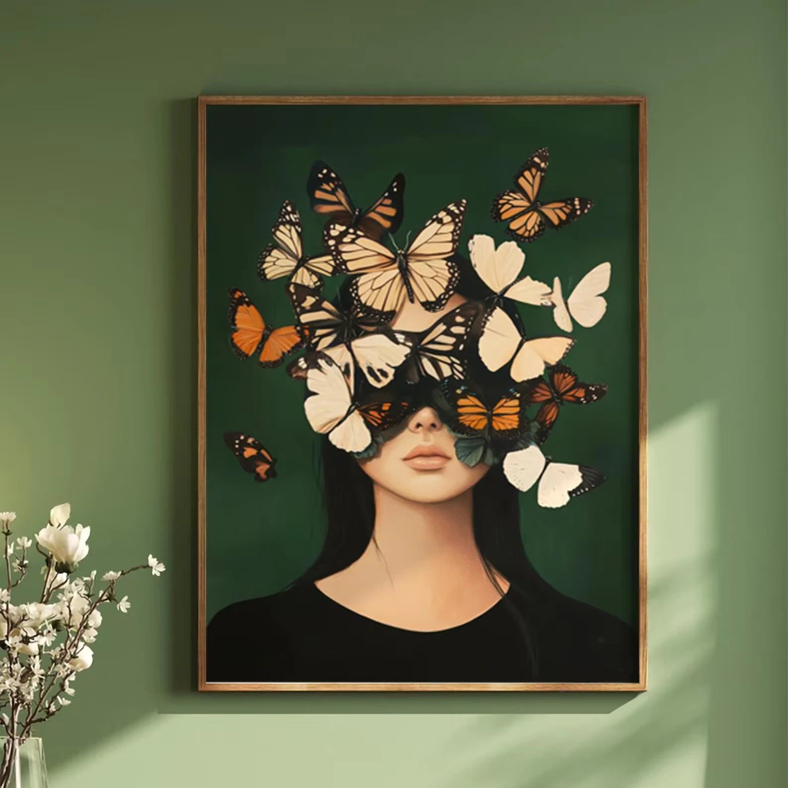 Framed artwork of a woman's face with butterflies on a green wall.