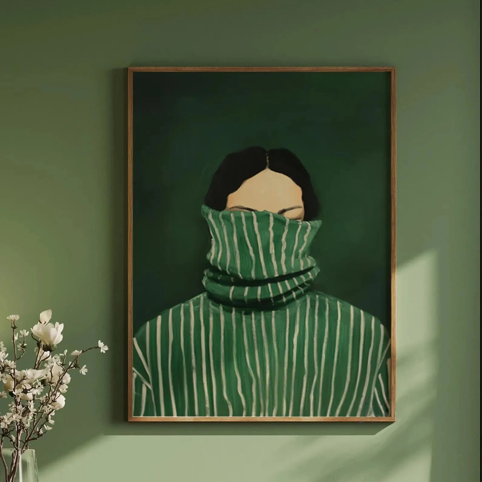 Framed artwork of a person wearing a green sweater with white stripes against a green wall.
