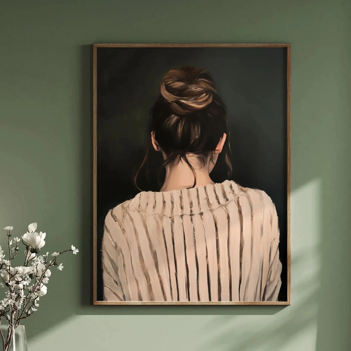 Framed artwork of a woman with braided hair against a dark background, displayed on a green wall.