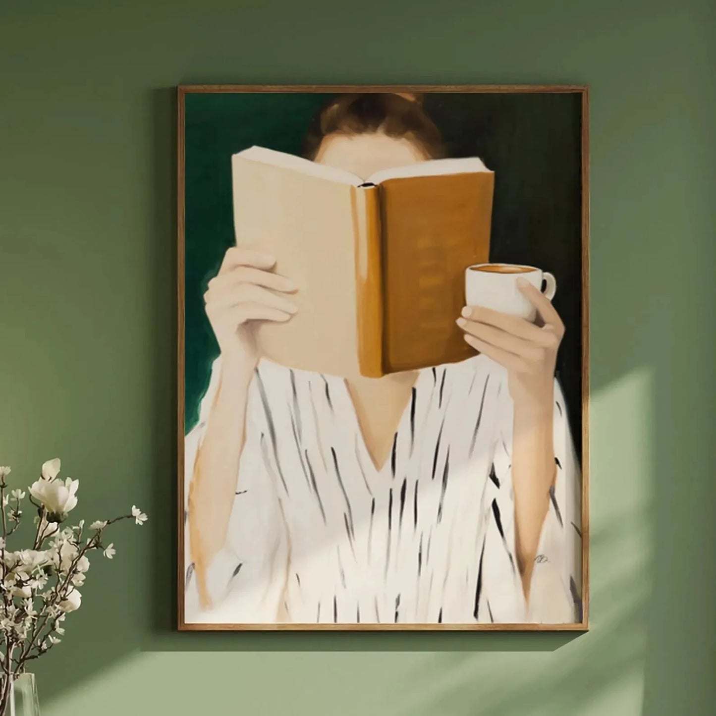 Framed artwork of a person reading a book with a cup against a green wall.