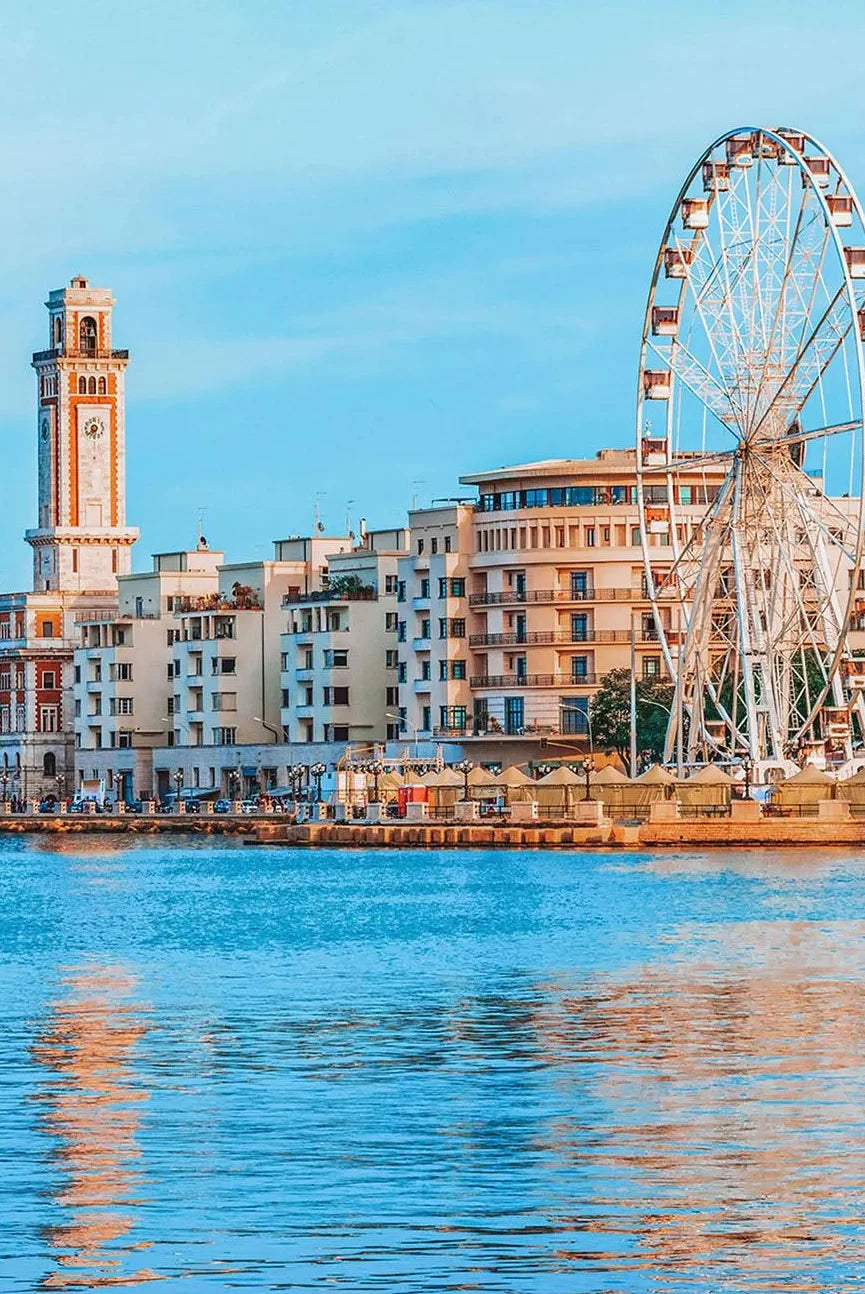 Cityscape with a clock tower and Ferris wheel by a body of water