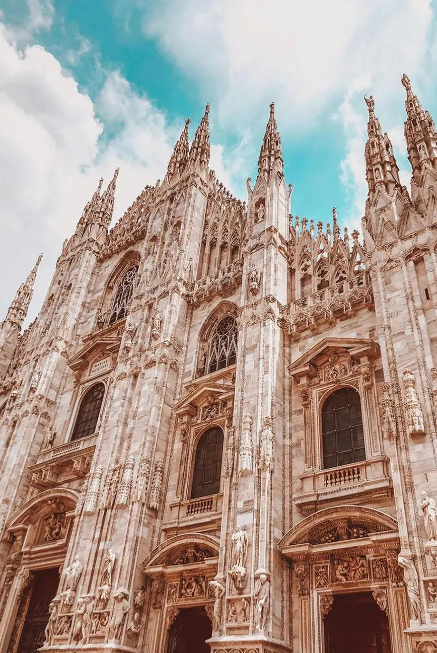 Gothic cathedral with intricate architecture against a blue sky with clouds
