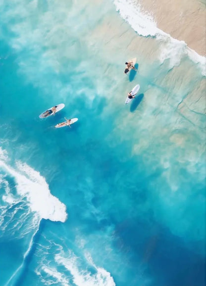 People paddleboarding on a clear blue ocean with a sandy beach in the background.