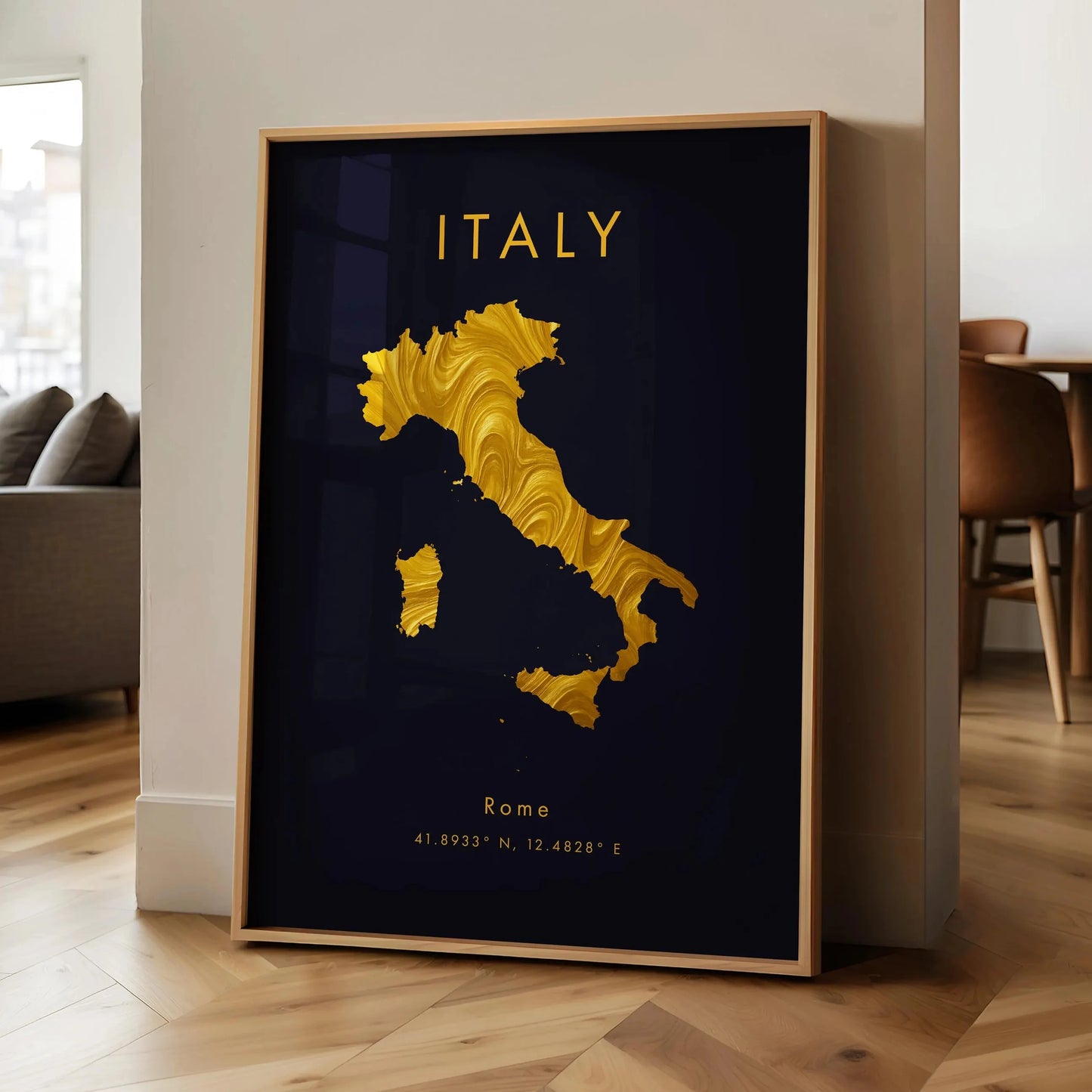 Framed artwork of Italy with gold map and 'Italy' text on a dark background, leaning against a wall.