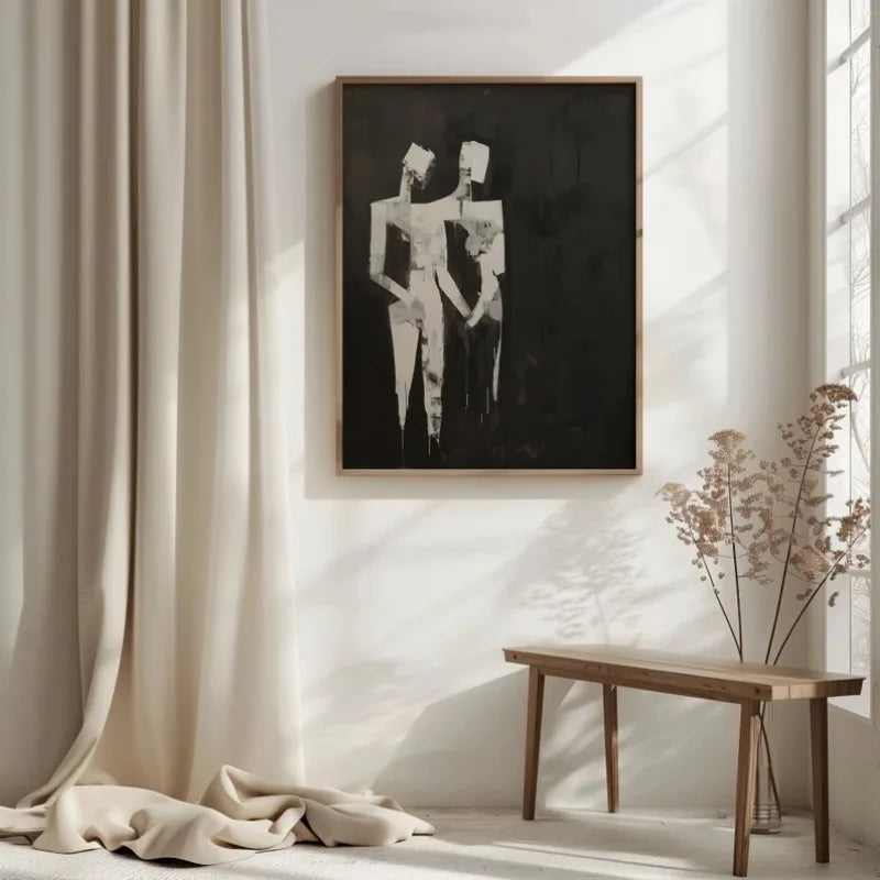 Framed black and white abstract art on a wall with a wooden table and draped fabric in a room.