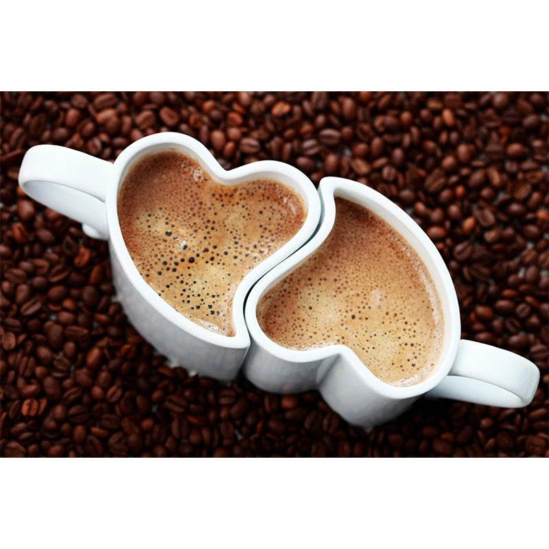 Two heart-shaped coffee mugs filled with coffee on a bed of coffee beans.