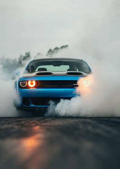 Blue car performing a burnout with smoke on a road