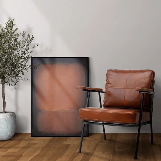 Brown leather chair in a room with a plant and abstract art on the wall. Canvas & Curio