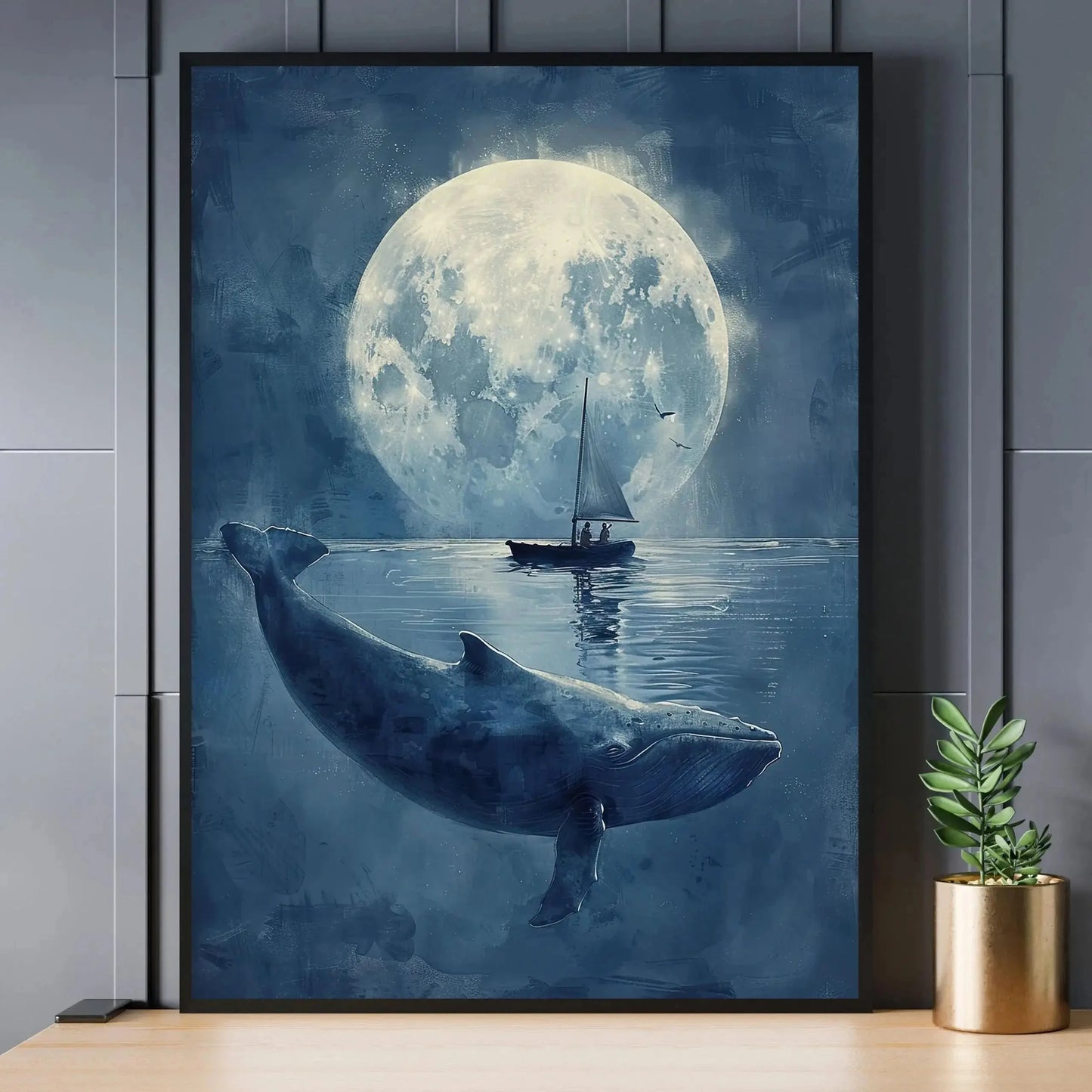 Framed artwork of a whale and sailboat under a large moon on a wall.