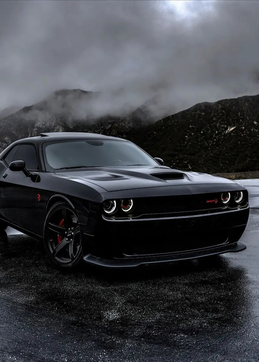 Black muscle car on a dark road with mountains in the background