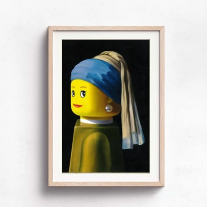 Framed artwork of a LEGO figure with a pearl earring on a white wall.