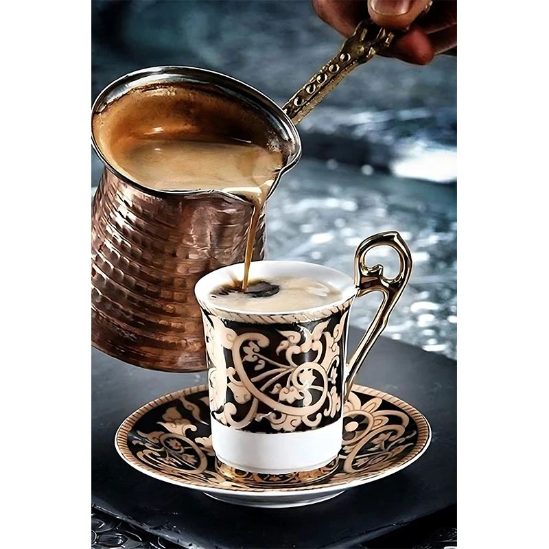 Copper pot pouring coffee into a decorative cup on a reflective surface