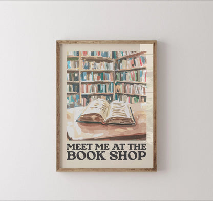 Framed artwork of a bookshelf with an open book and 'Meet Me at the Book Shop' text on a white wall.