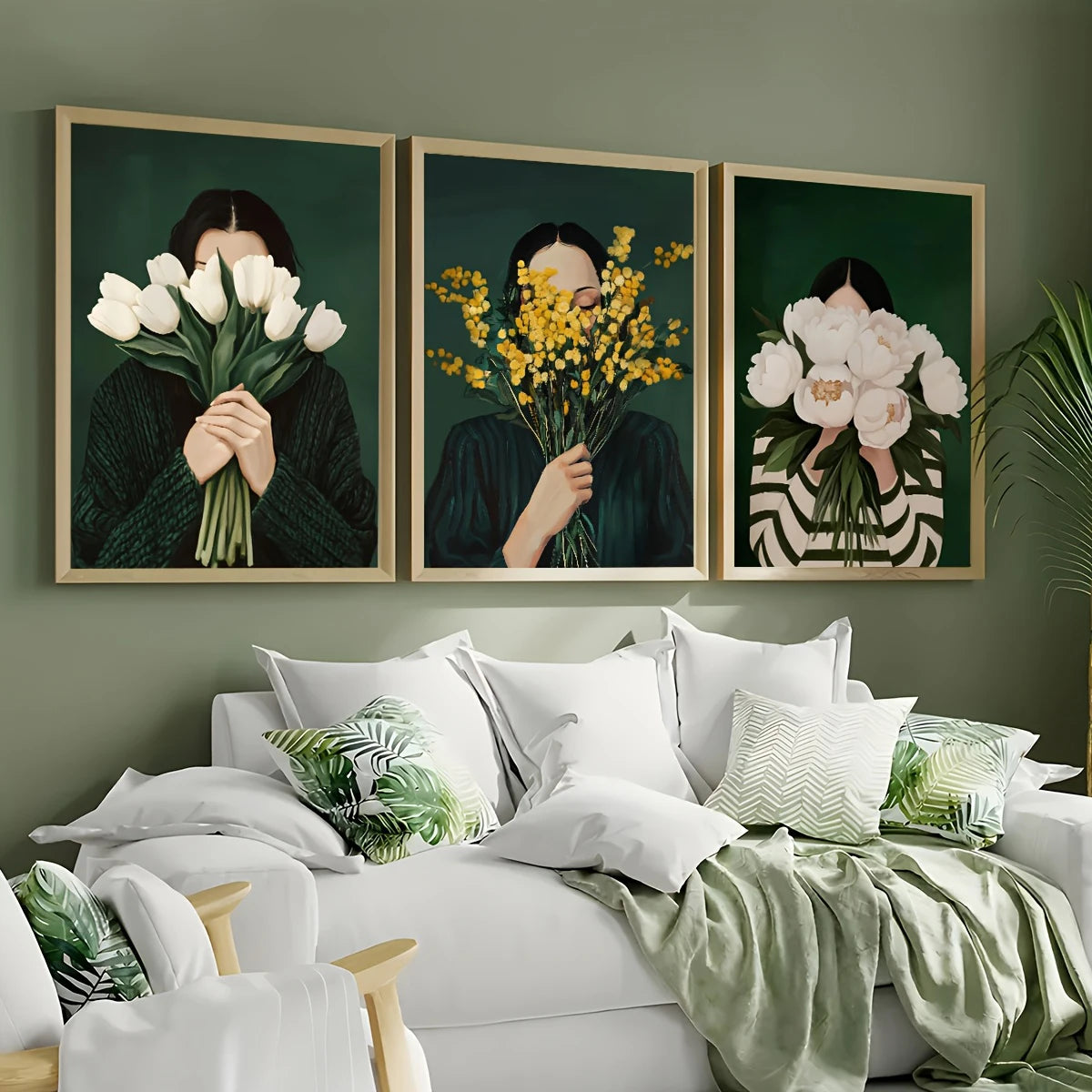 Three framed artworks of a person holding flowers above their face on a wall above a bed.