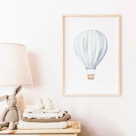 Framed artwork of a hot air balloon on a wall above a wooden surface with toys and blankets. Canvas & Curio