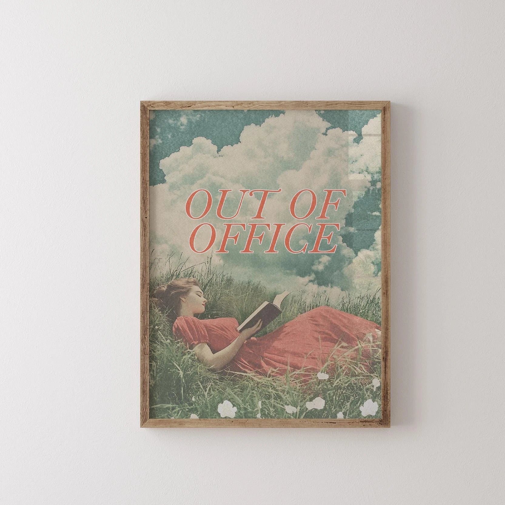 Framed artwork with a woman lying in grass reading a book, titled 'Out of Office'.