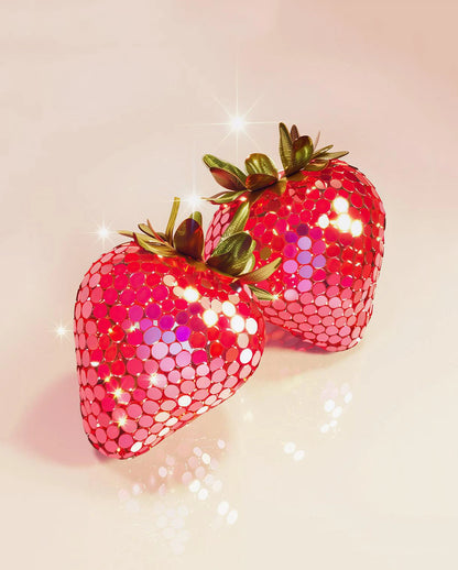 Two glittery strawberry-shaped objects on a light pink background