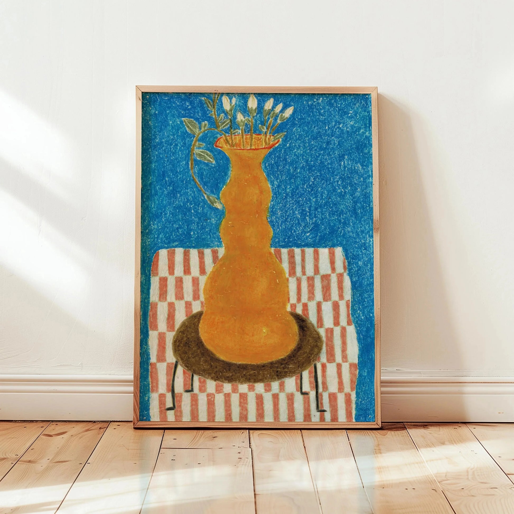 Framed artwork of a yellow vase with flowers on a striped table against a blue background, displayed on a wooden floor.