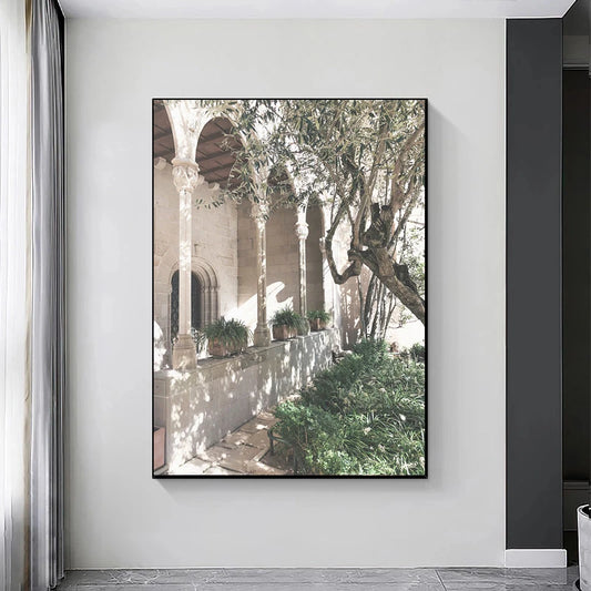 Framed artwork of a garden scene with arches and plants on a white wall. Canvas & Curio