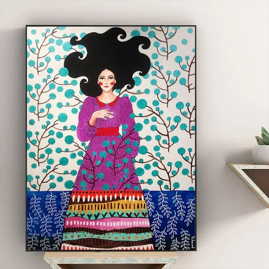 Framed artwork of a woman in a colorful dress with a decorative border on a wall. Canvas & Curio