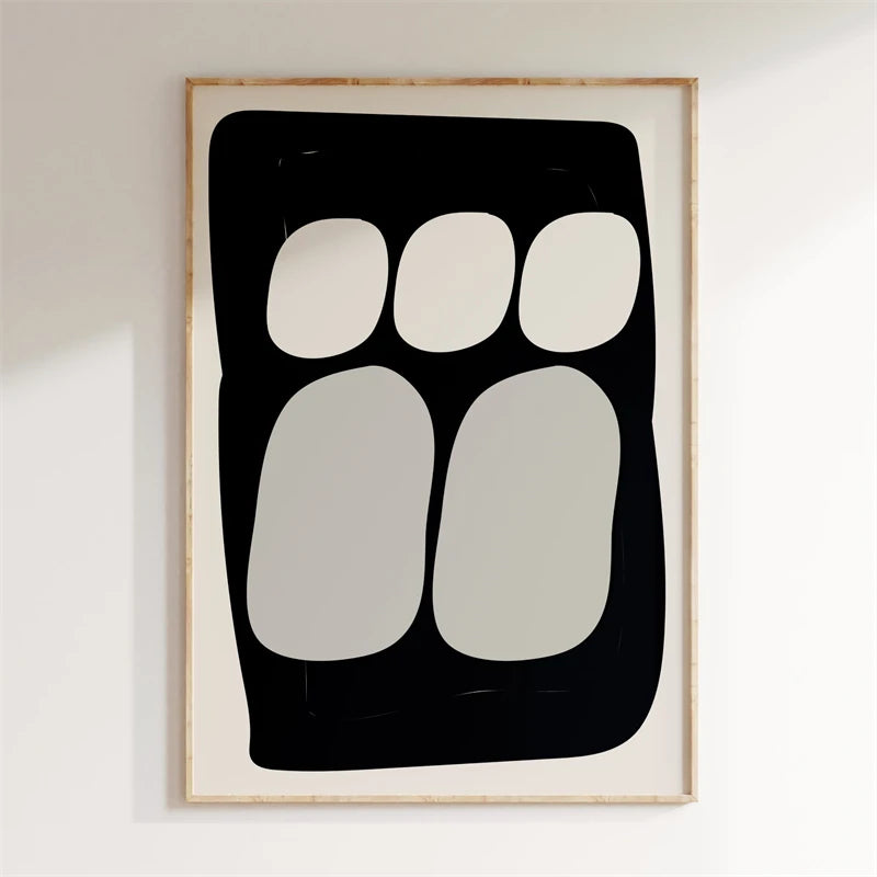 Framed abstract art print with black and white shapes on a white wall