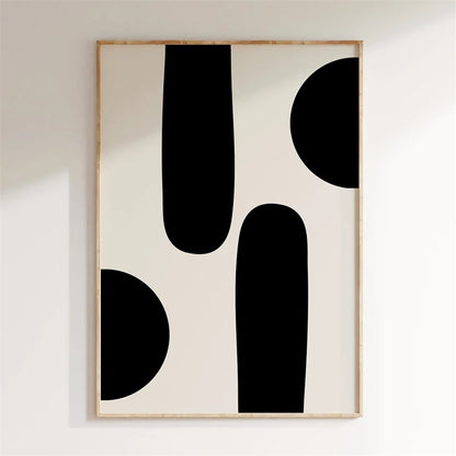 Framed abstract art with black shapes on a white wall