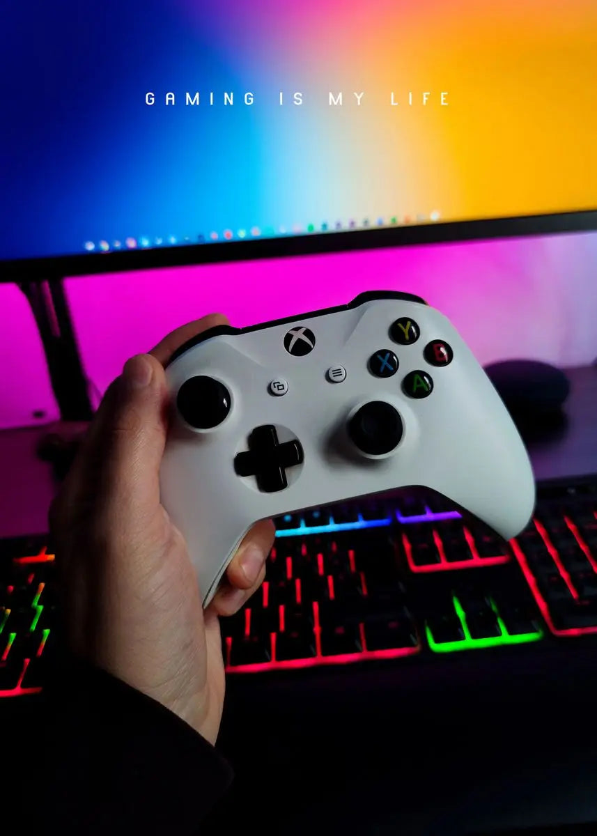Hand holding a gaming controller with a colorful monitor and keyboard in the background, featuring the text 'Gaming is my life'.