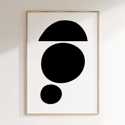 Framed abstract art with black shapes on a white wall