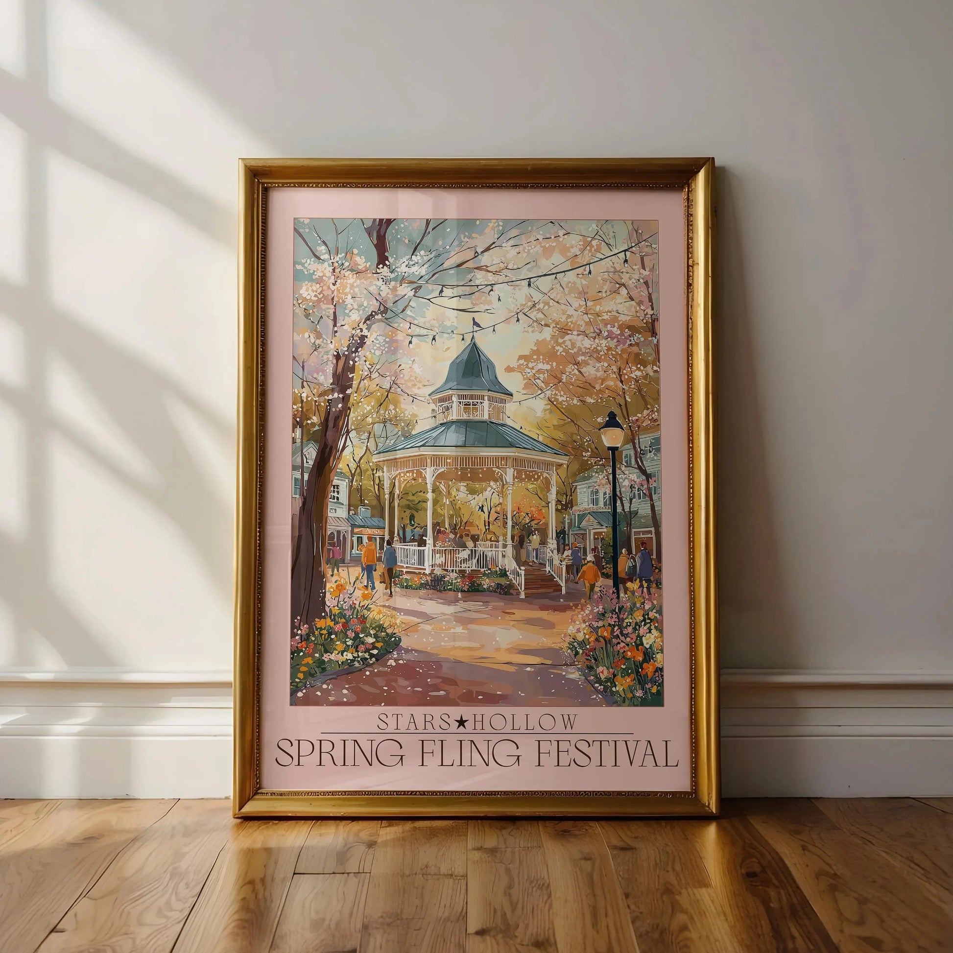 Framed artwork of a gazebo in a park with cherry blossoms, titled 'Stars Hollow Spring Fling Festival'.