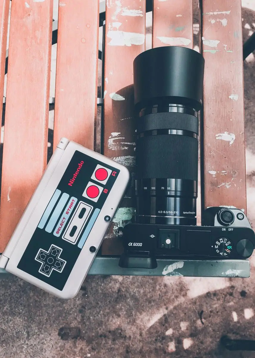Camera with lens and Nintendo Entertainment System controller on a textured surface