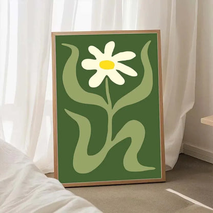 Framed artwork of a white flower with green leaves on a green background, placed indoors.
