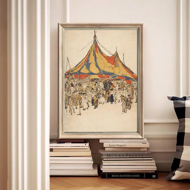 Framed artwork of a circus scene on a stack of books against a white wall.