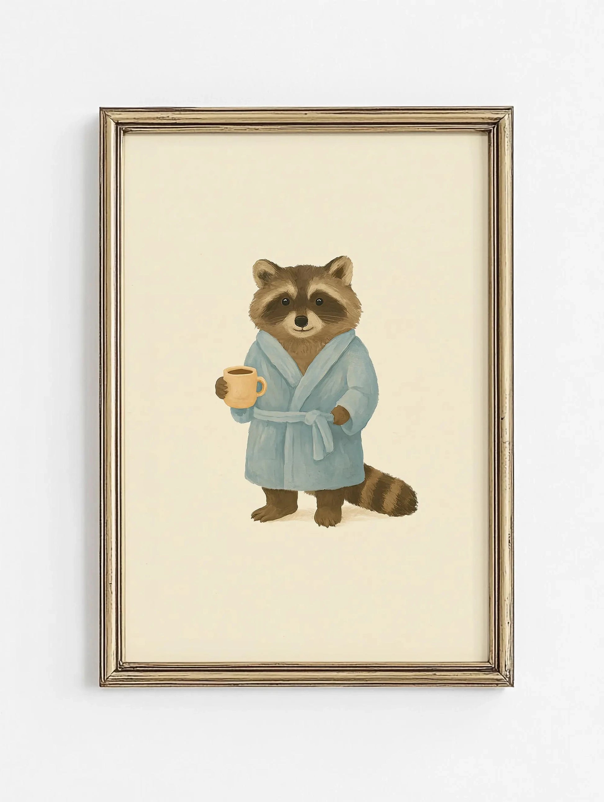 Framed artwork of a raccoon in a blue robe holding a cup on a beige background