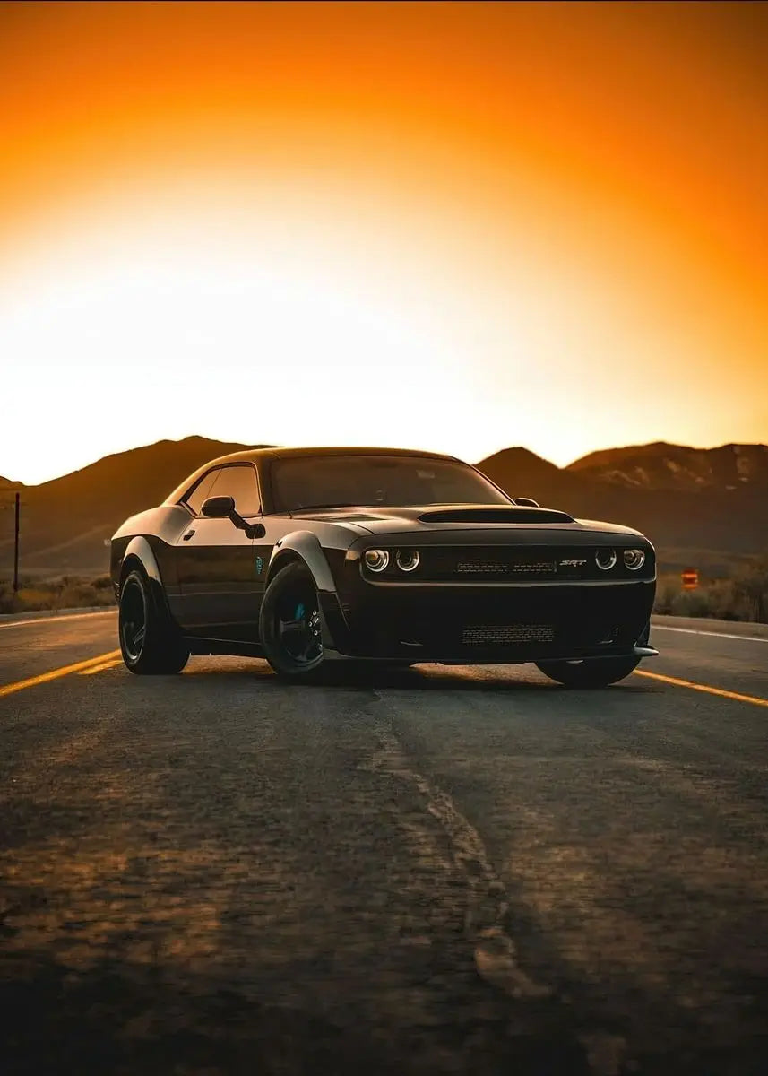 Black muscle car on a desert road with an orange sunset
