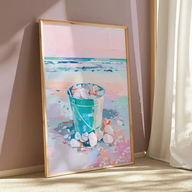 Framed artwork of a beach scene with a bucket and seashells on a pastel background.