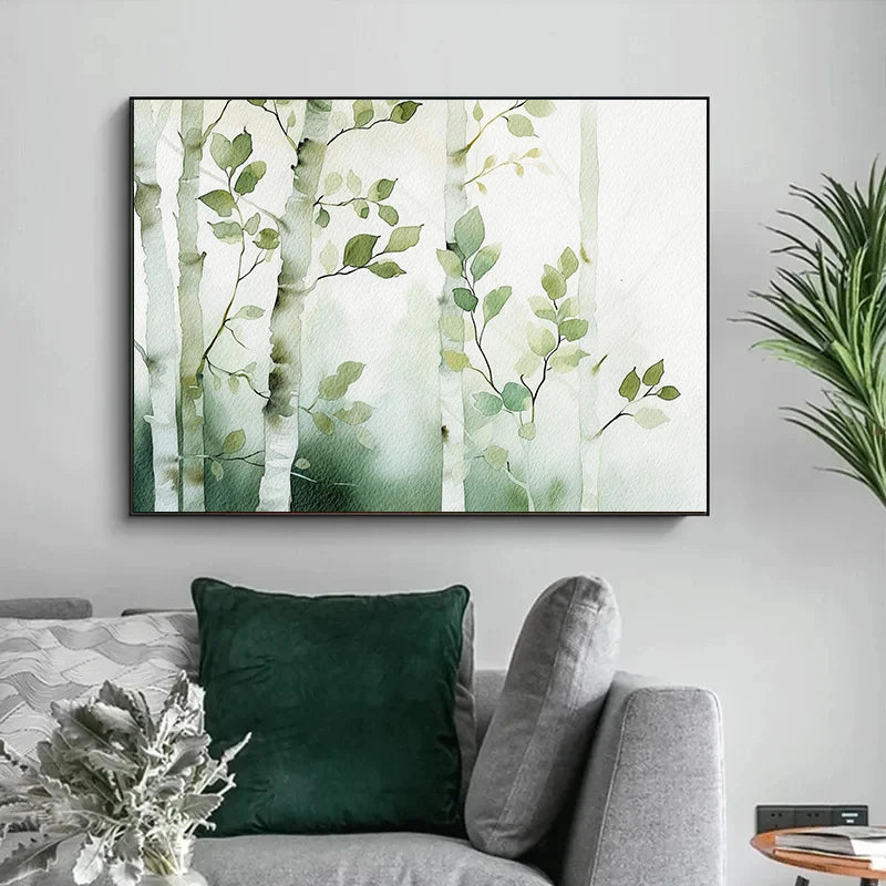 Framed artwork of green leaves on a wall above a gray sofa with green cushions.