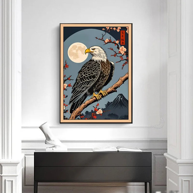 Framed artwork of an eagle on a branch with cherry blossoms and a moon in the background, displayed on a wall above a desk.