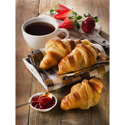 Croissants with a cup of coffee and strawberries on a wooden table