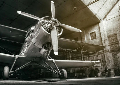 Vintage airplane with a propeller inside a hangar.