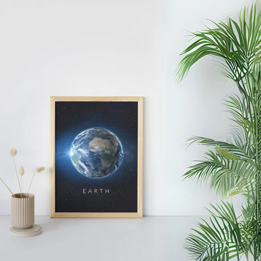 Framed print of Earth on a white wall with a plant and vase in the foreground Canvas & Curio