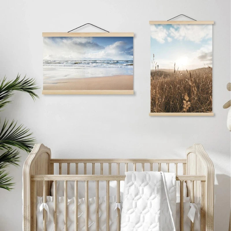 Wooden crib with white bedding in a room with framed beach and field prints on the wall.