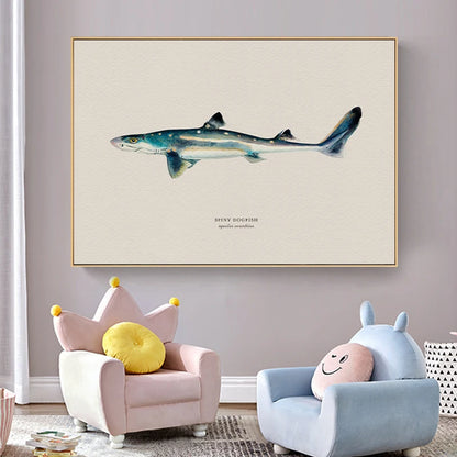 Framed artwork of a shark on a wall above two children's chairs with colorful cushions.