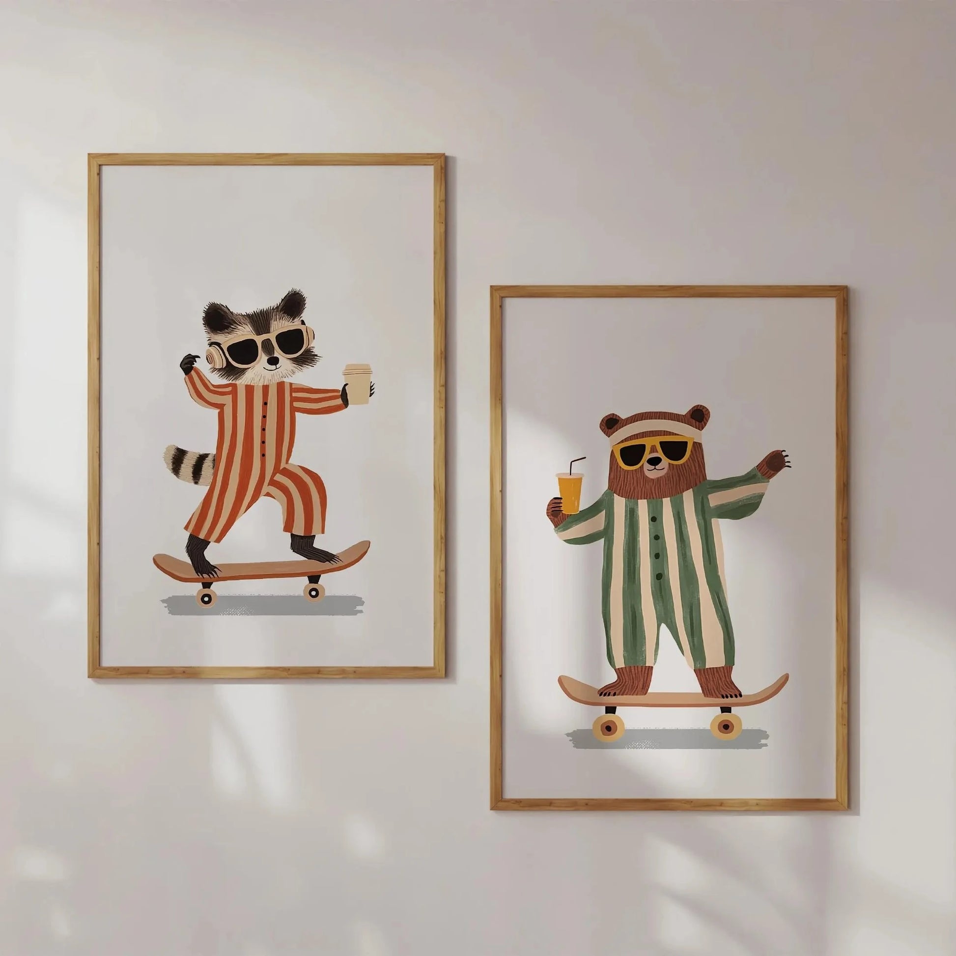 Two framed illustrations of a raccoon and a bear on skateboards with sunglasses and drinks, on a white wall.